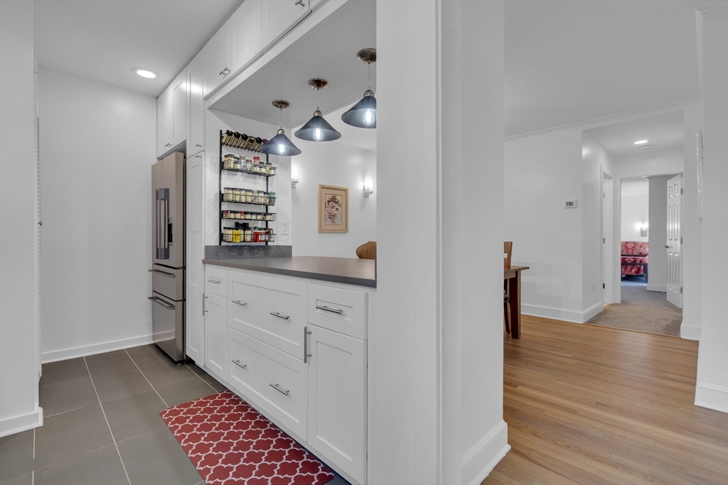 232 Summit Avenue, Unit A1 Brookline, MA 02446 - Photo 9 of 29 a hall with kitchen island white cabinets and wooden floor