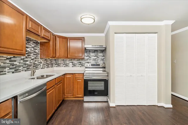 a kitchen with a sink cabinets stainless steel appliances and wooden floor
