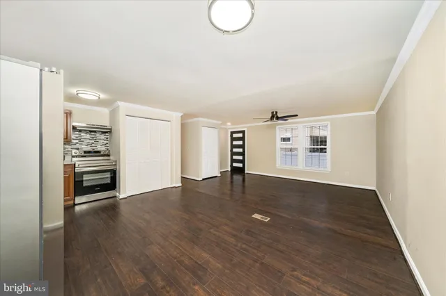 an empty room with wooden floor cabinet and windows