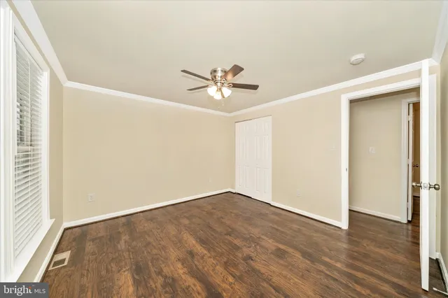 an empty room with wooden floor and ceiling fan