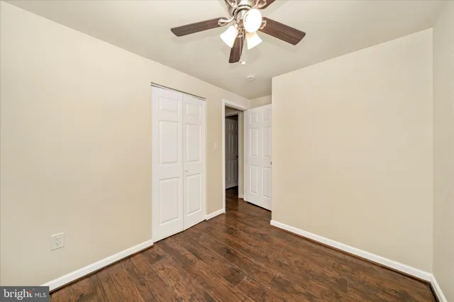 an empty room with wooden floor closet and fan