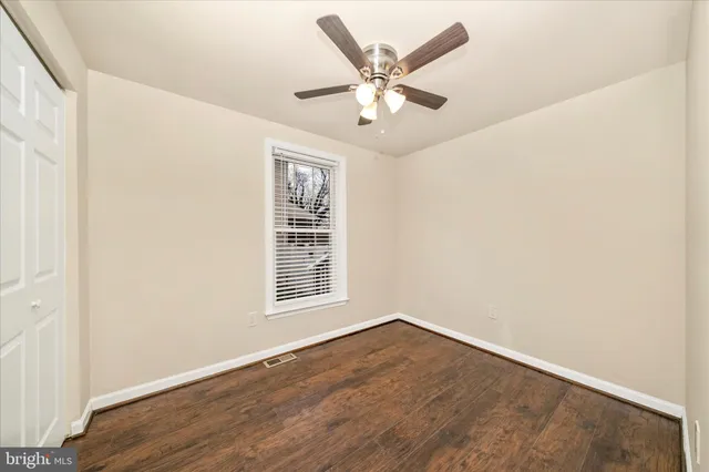 an empty room with wooden floor chandelier fan and windows