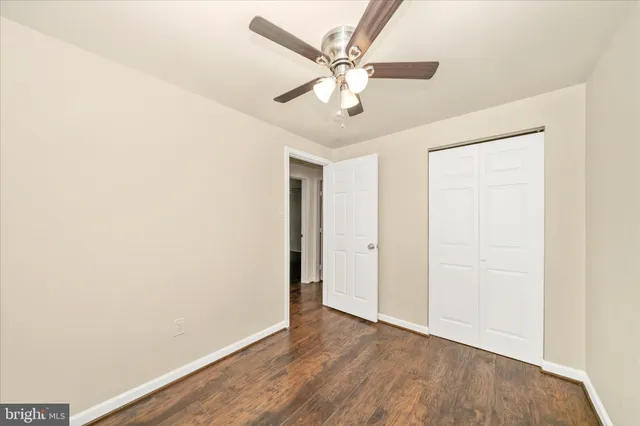 an empty room with wooden floor and ceiling fan