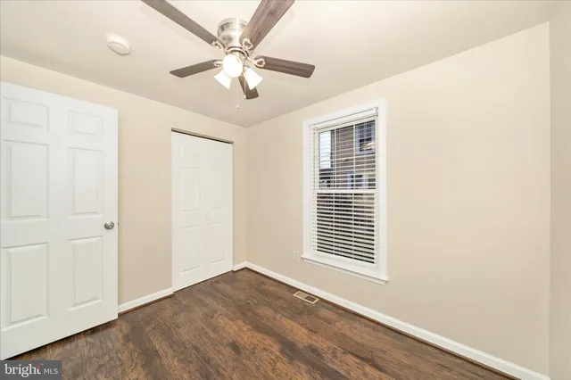 an empty room with wooden floor chandelier fan and windows