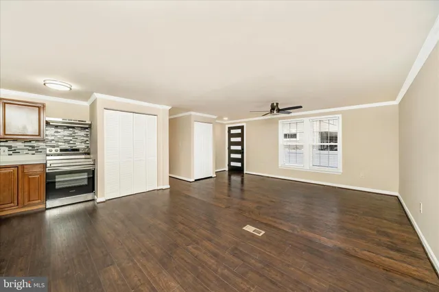 a view of an empty room with a window and wooden floor