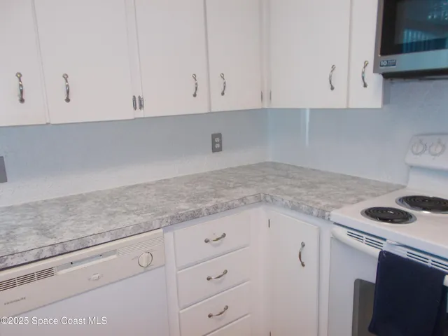 a kitchen with granite countertop white cabinets and a stove