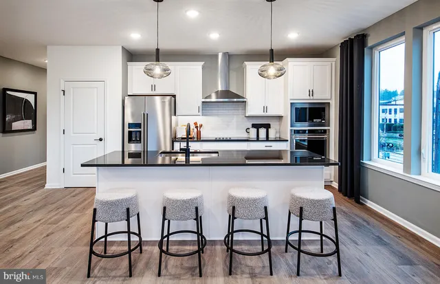 a kitchen with stainless steel appliances granite countertop a kitchen island a stove and a refrigerator