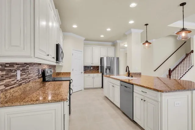 a kitchen with white cabinets and sink