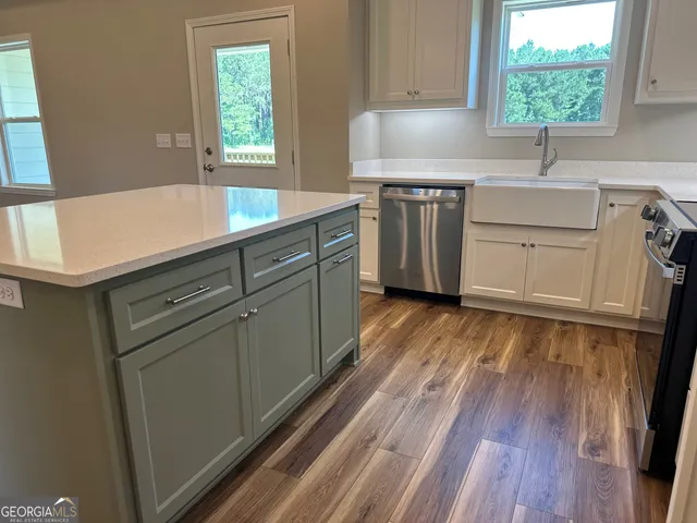 a kitchen with stainless steel appliances granite countertop a sink a stove a refrigerator wooden floor and cabinets