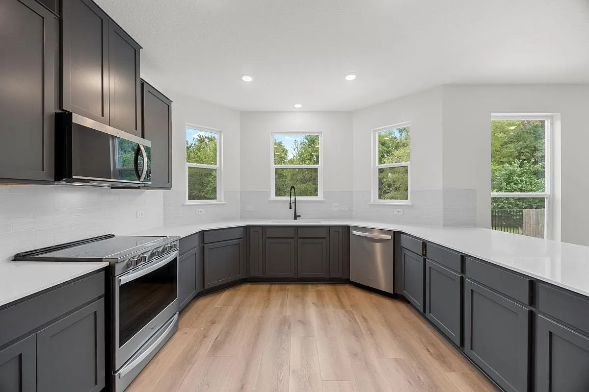 612 St Cindy's Way Pflugerville, TX 78660 - Photo 6 of 6 Modern kitchen with sleek dark cabinetry, white countertops, and warm wood flooring.