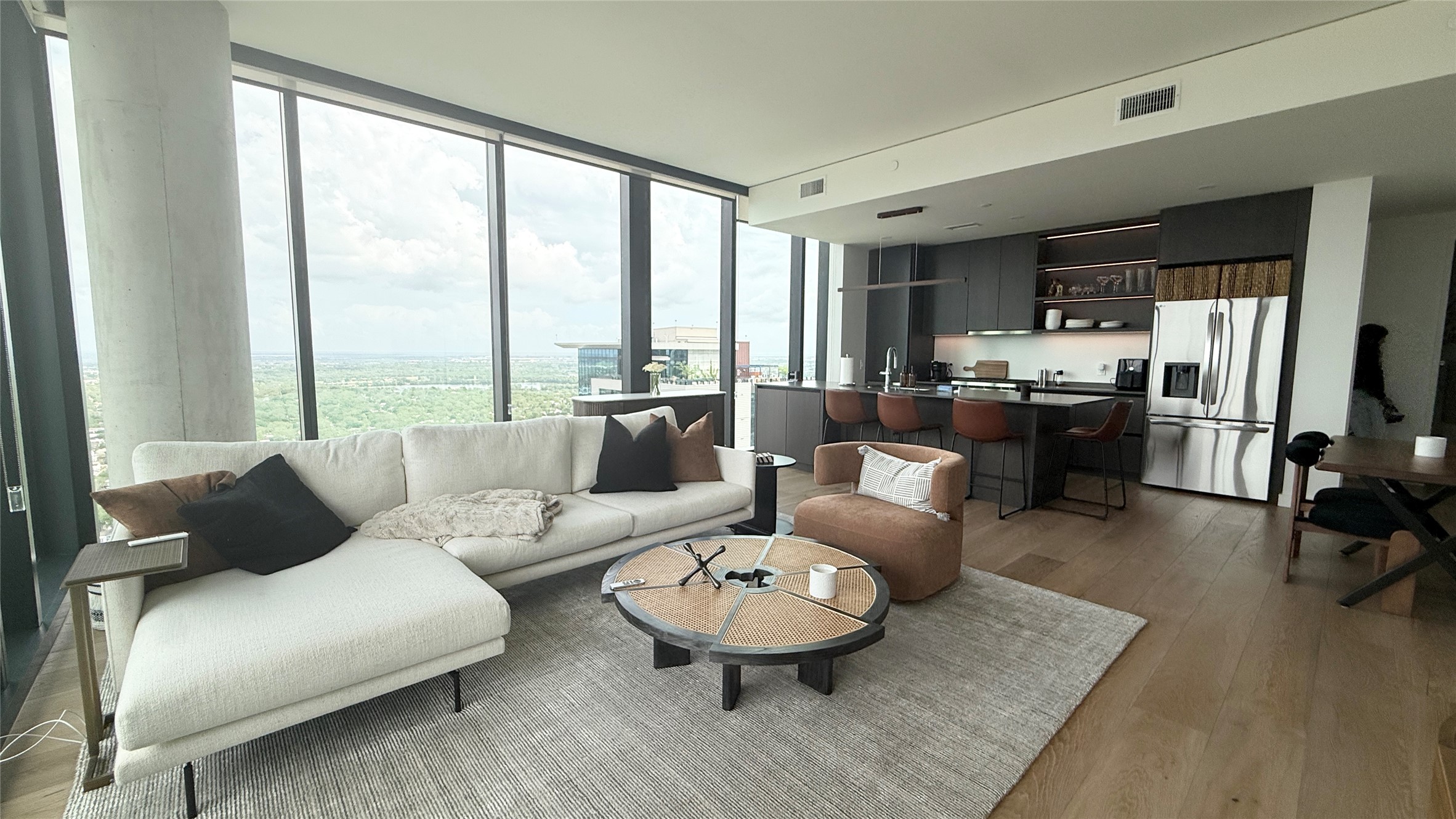 610 Davis Street, Unit 4007 Austin, TX 78701 - Photo 4 of 29 Open concept living area featuring floor-to-ceiling windows, hardwood flooring, and a modern kitchen with a stainless steel refrigerator and dark cabinetry