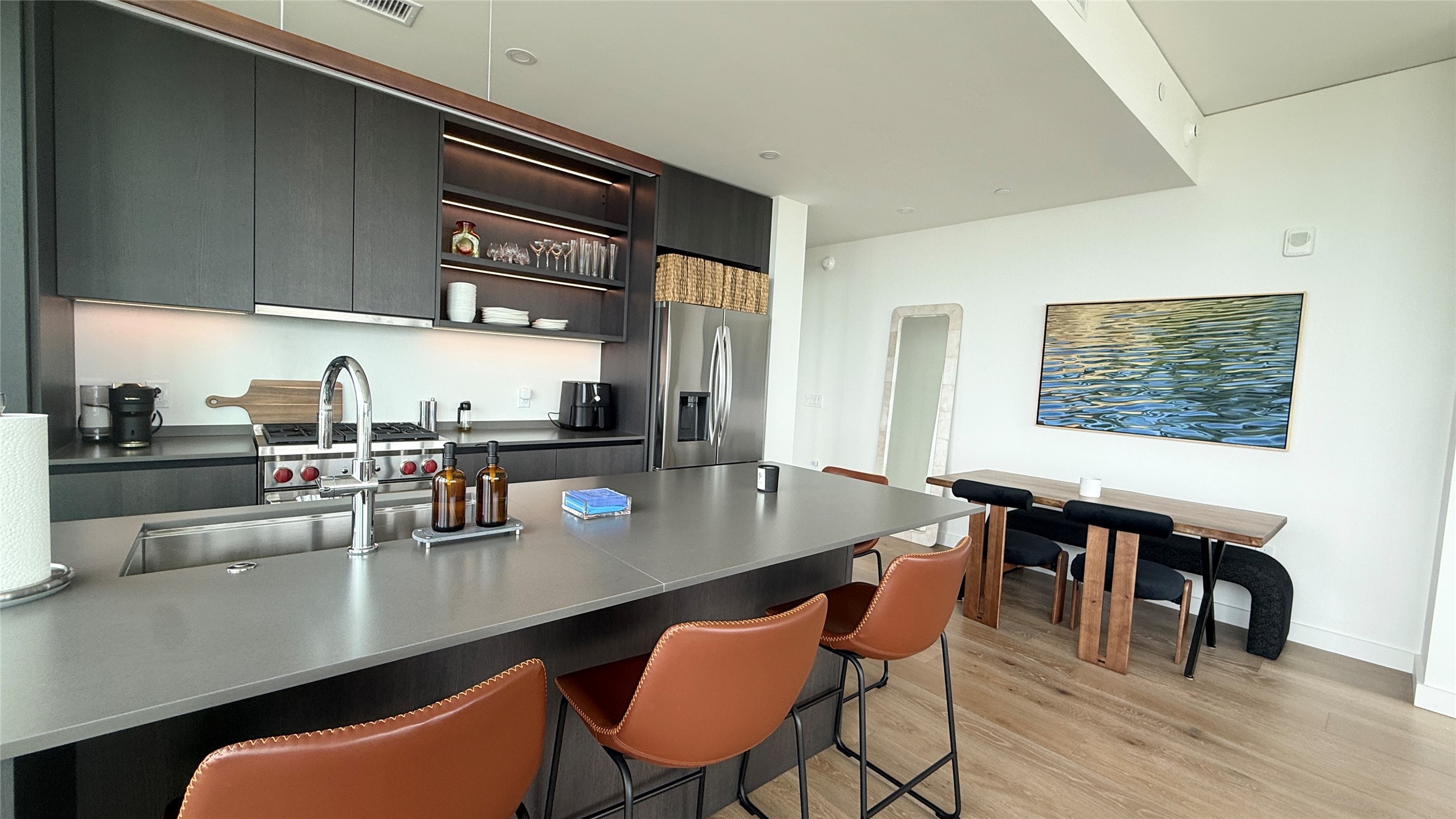 610 Davis Street, Unit 4007 Austin, TX 78701 - Photo 7 of 29 The kitchen features dark cabinetry, a spacious island with seating, a stainless steel sink, and a stainless steel refrigerator