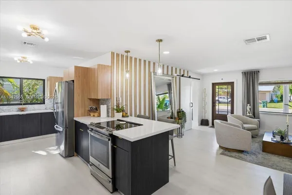 a large kitchen with kitchen island a large counter top space a sink a window and stainless steel appliances