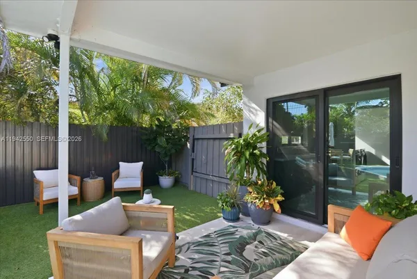 a view of a backyard with chairs and potted plants