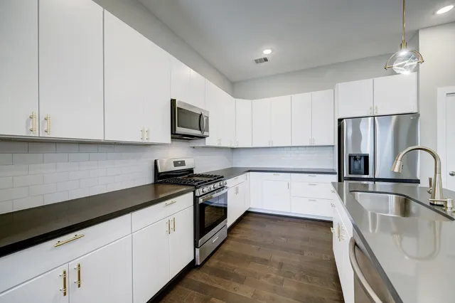 a large kitchen with stainless steel appliances granite countertop a stove a sink and a microwave