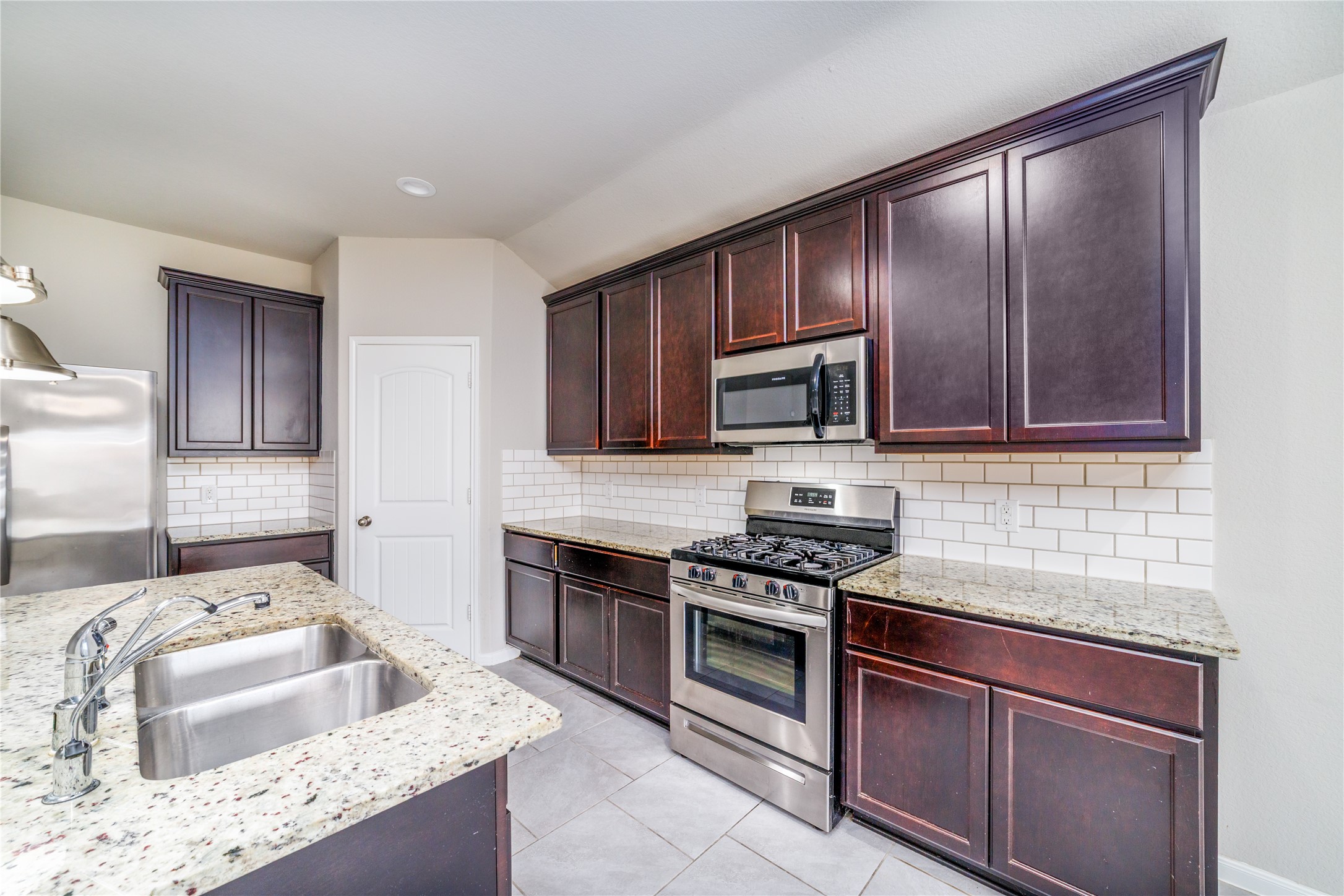 8307 Oakleaf Meadow Court Rosharon, TX 77583 - Photo 13 of 39 a kitchen with granite countertop stainless steel appliances wooden cabinets a stove top oven and a granite counter tops