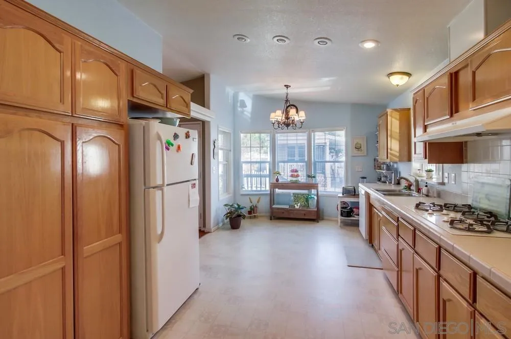 8301 Mission Gorge Road, Unit 248 Santee, CA 92071 - Photo 6 of 24 a kitchen with refrigerator a stove and a wooden cabinets