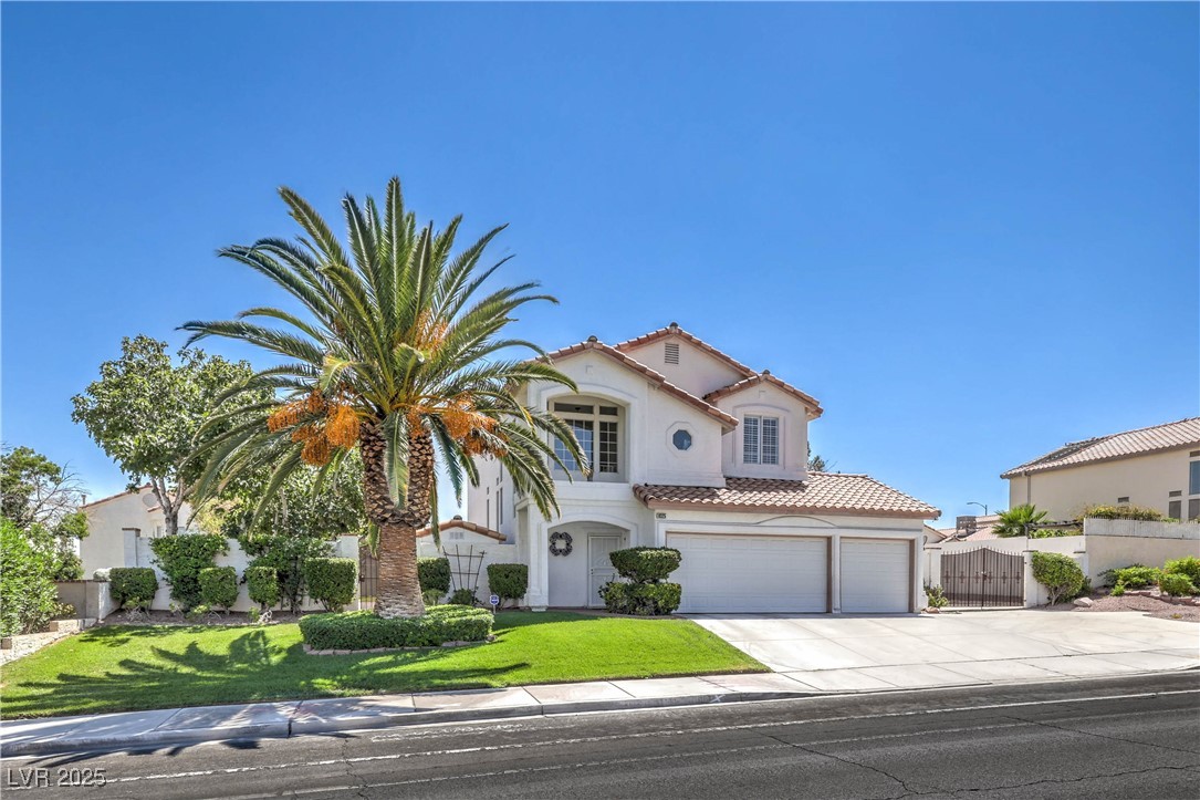 8325 Alta Drive Las Vegas, NV 89145 - Photo 2 of 31 Mediterranean / spanish home featuring concrete driveway, stucco siding, a tiled roof, a garage, and a gate