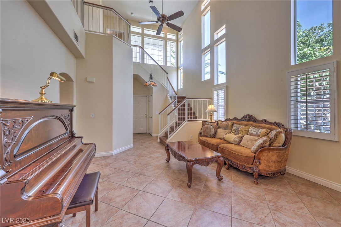 8325 Alta Drive Las Vegas, NV 89145 - Photo 4 of 31 Living area with light tile patterned flooring, a ceiling fan, stairway, and a high ceiling