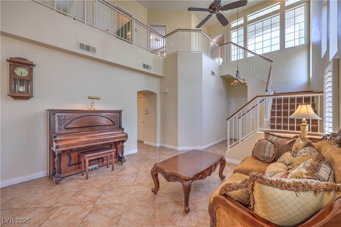8325 Alta Drive Las Vegas, NV 89145 - Photo 5 of 31 Tiled living room featuring a high ceiling, arched walkways, ceiling fan, and stairway
