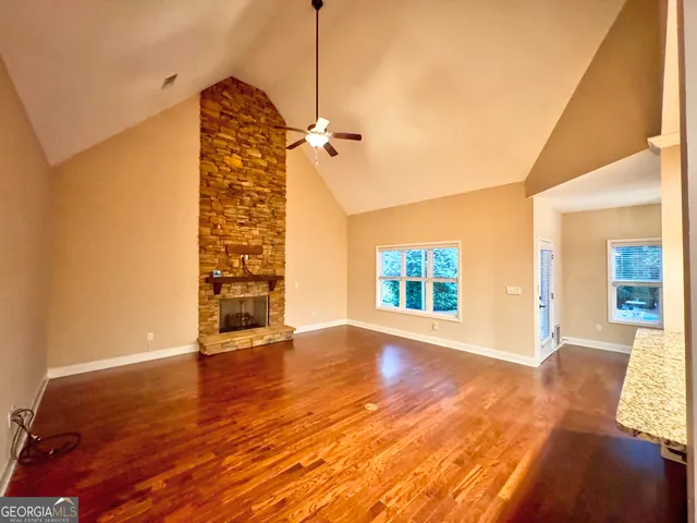 a view of an empty room with window and wooden floor