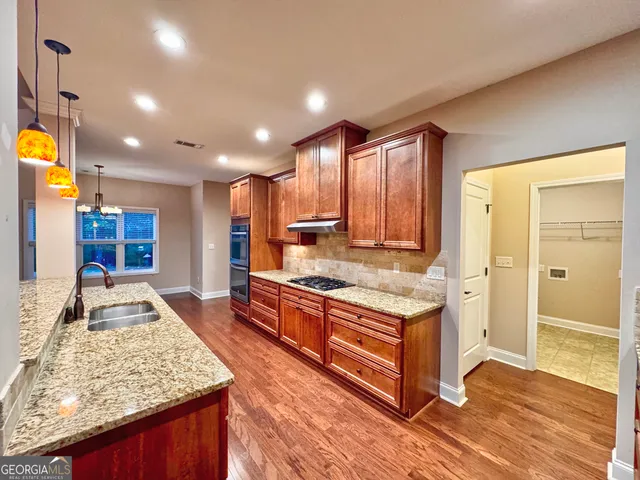 a kitchen with stainless steel appliances granite countertop a stove and a wooden floors