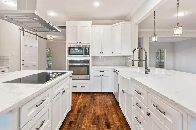 a large white kitchen with a stove top oven a chimney wooden floor and cabinets