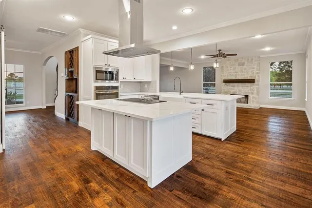 a large kitchen with stainless steel appliances a large counter top and a wooden floors