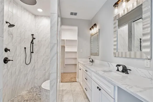 a bathroom with a granite countertop sink a mirror a vanity and shower