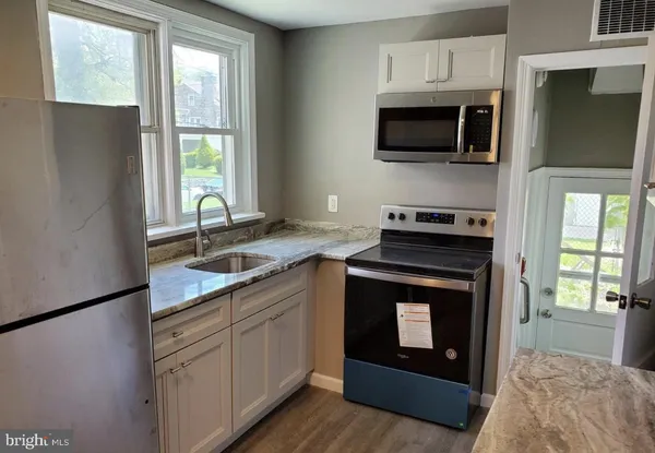 a kitchen with stainless steel appliances granite countertop a refrigerator a stove a sink and a microwave