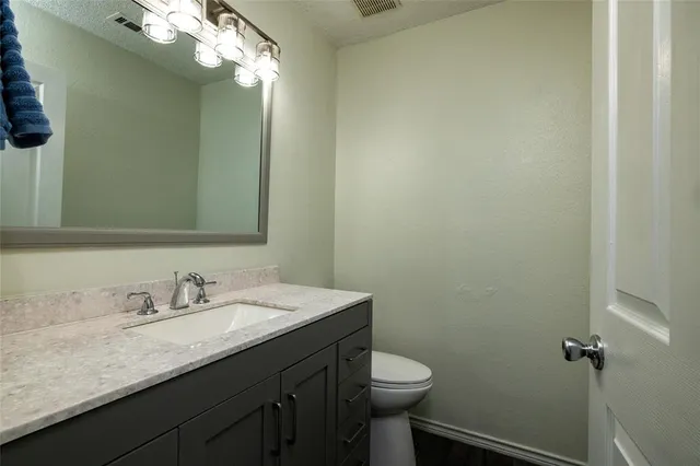 a bathroom with a granite countertop sink a toilet and a mirror