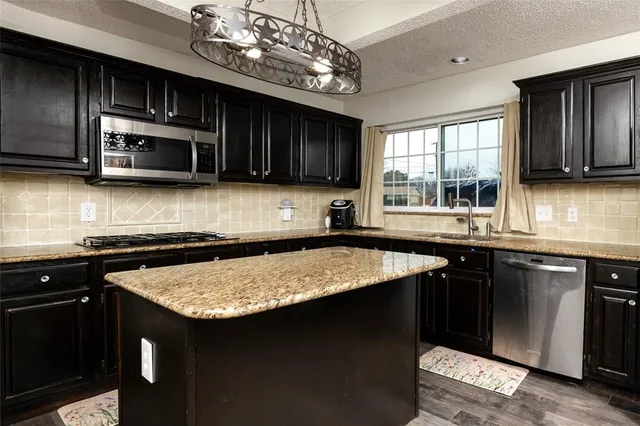 a kitchen with stainless steel appliances granite countertop a sink stove and cabinets