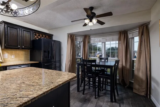 a kitchen with stainless steel appliances granite countertop a stove a refrigerator a sink a dining table and chairs with wooden floor