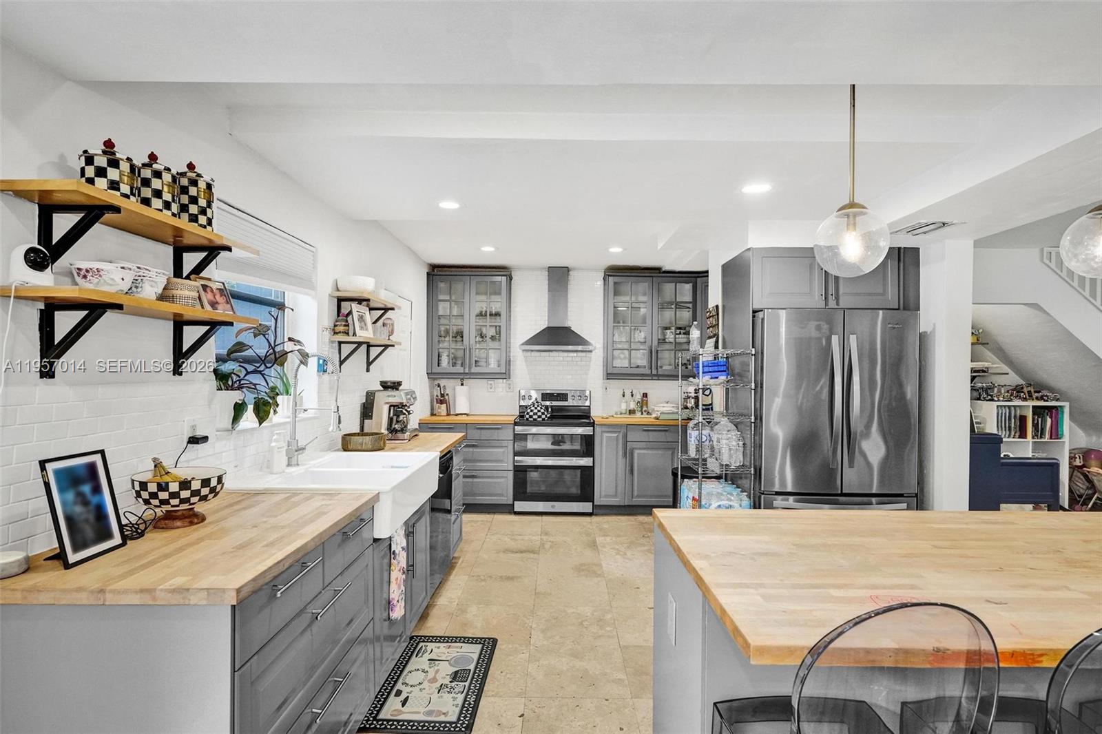 1165 99th Street, Unit 2 Bay Harbor Islands, FL 33154 - Photo 8 of 10 a large kitchen with kitchen island a stove a sink dishwasher a dining table and chairs with wooden floor