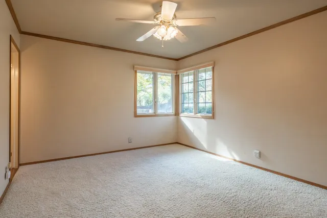 an empty room with windows and ceiling fan