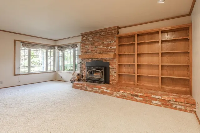 a view of an empty room with a fireplace and a window