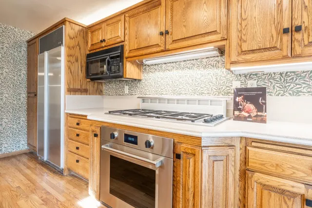 a kitchen with stainless steel appliances granite countertop a stove a sink and a microwave