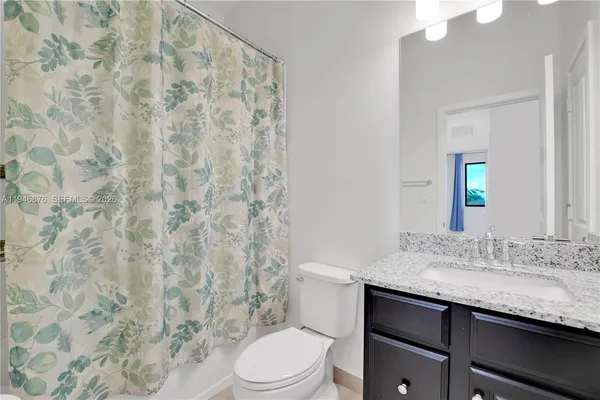 a bathroom with a granite countertop sink mirror vanity and toilet