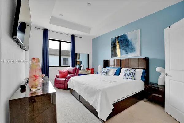 a bedroom with a bed and flat tv screen on the dresser