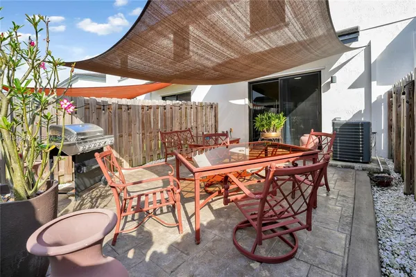 a patio with table and chairs with potted plants