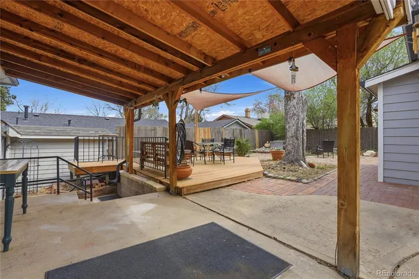 a view of a backyard with table and chairs potted plants and wooden fence