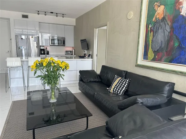 a living room with stainless steel appliances furniture and a view of kitchen