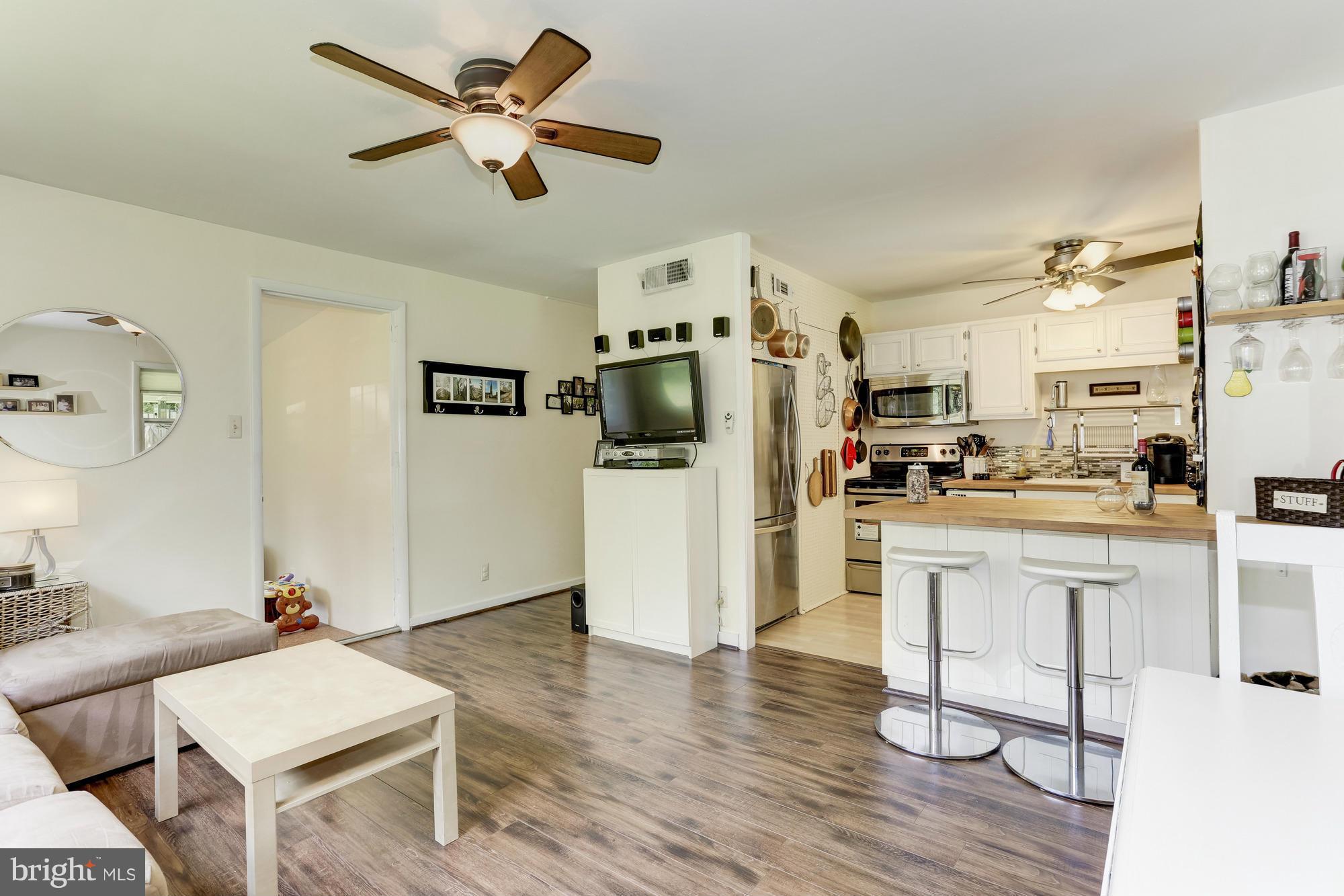 23 Ericsson Road Cabin John, MD 20818 - Photo 4 of 30 a kitchen with stainless steel appliances kitchen island granite countertop a refrigerator a stove top oven a sink dishwasher and a dining table with wooden floor