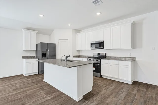 a kitchen with granite countertop a sink stove and refrigerator