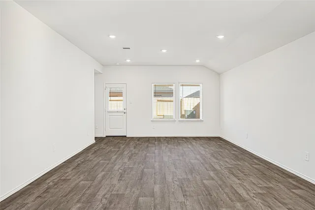 a view of kitchen and empty room with wooden floor