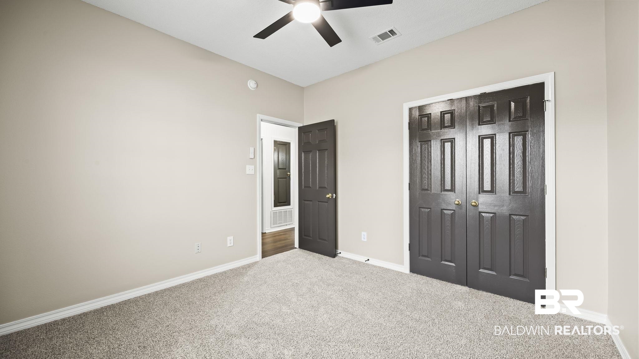 2651 South Juniper Street, Unit 705 Foley, AL 36535 - Photo 14 of 37 Carpeted interior space featuring light neutral wall tones, white baseboards, and a dark ceiling fan