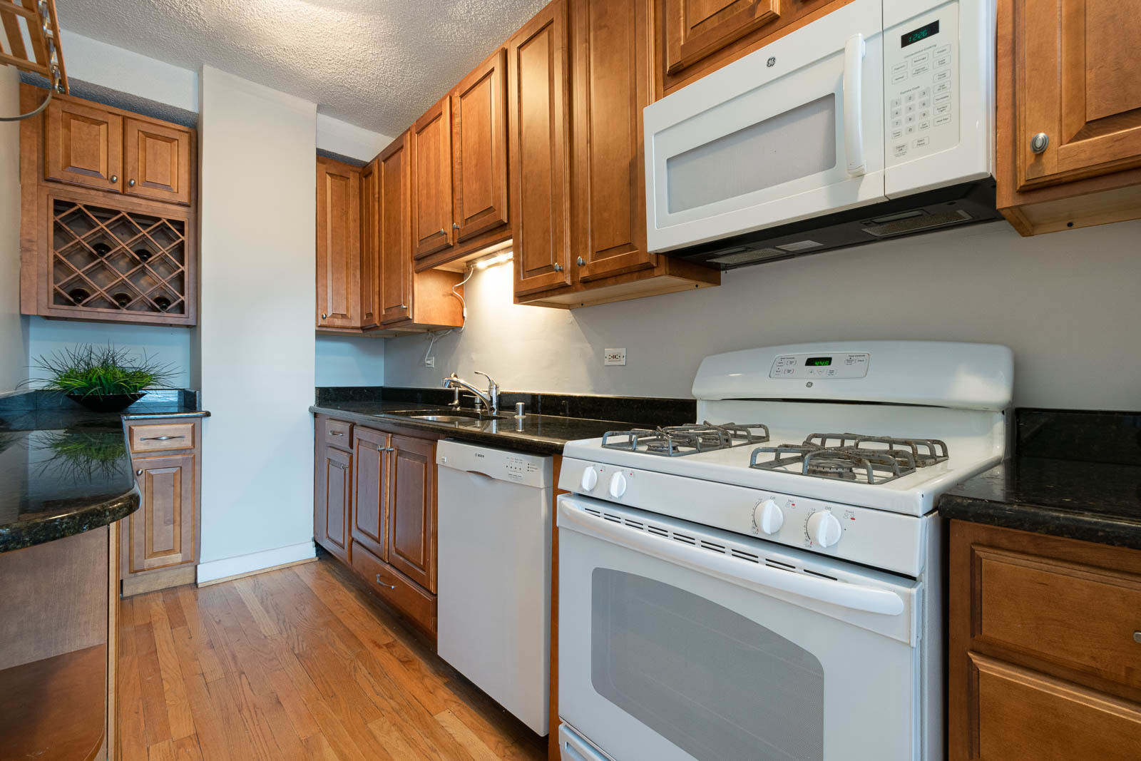 725 West Sheridan Road, Unit 206 Chicago, IL 60613 - Photo 4 of 13 a kitchen with granite countertop cabinets stainless steel appliances and wooden floor