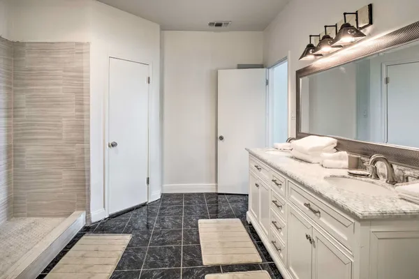 a bathroom with a granite countertop sink a mirror and a shower