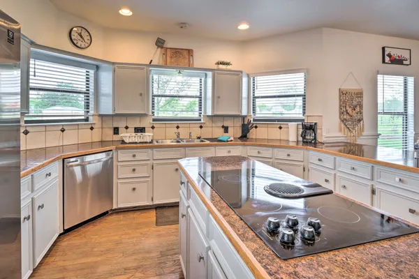 a kitchen with stainless steel appliances granite countertop a sink a stove a refrigerator cabinets and a window