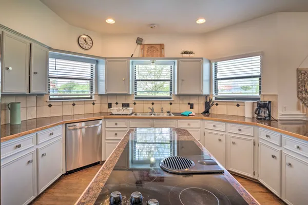 a large kitchen with kitchen island granite countertop a sink and white cabinets